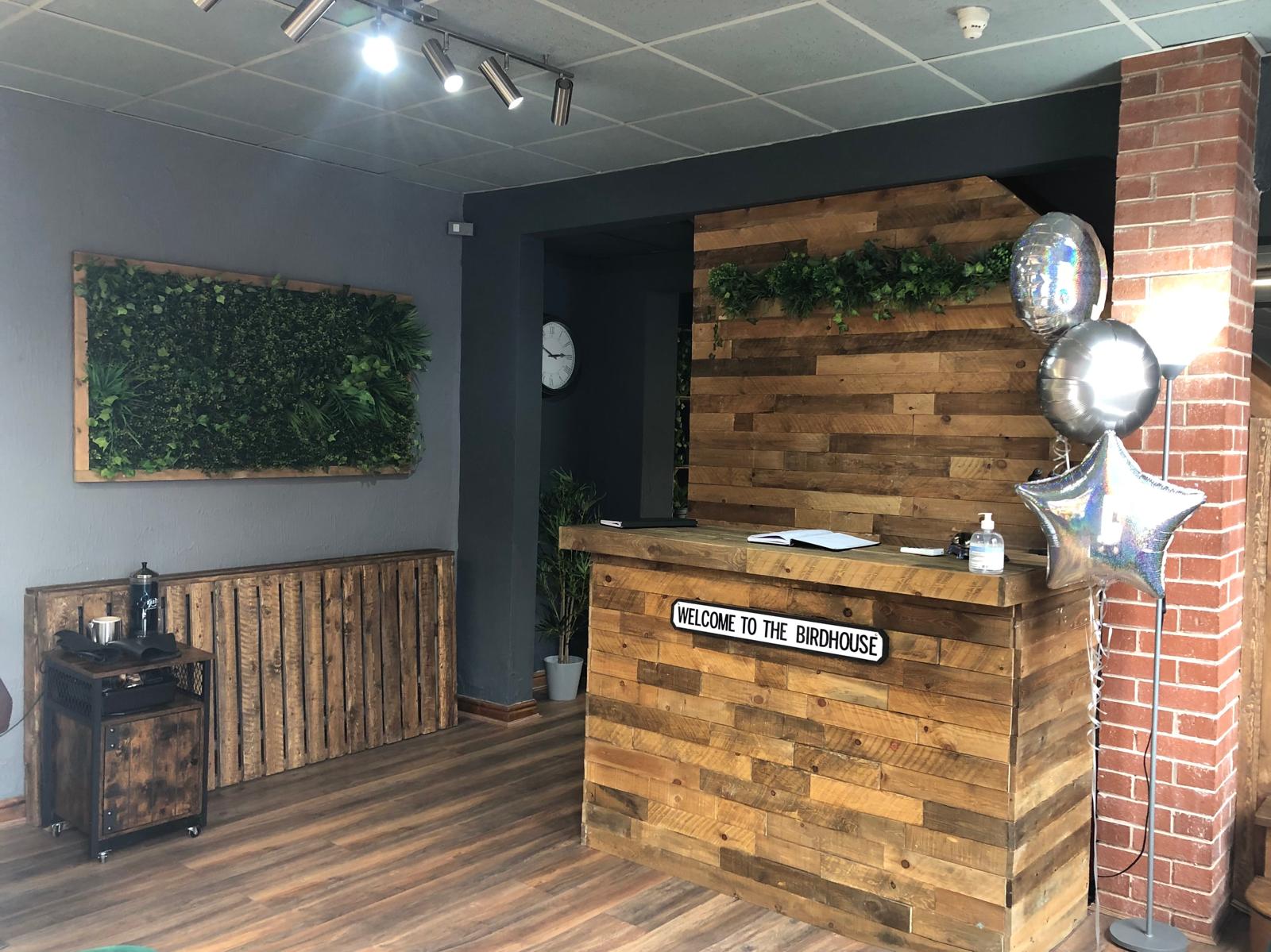The Birdhouse Hair Room Reception Desk, with a street sign attached to the desk saying 'Welcome to Birdhouse'.